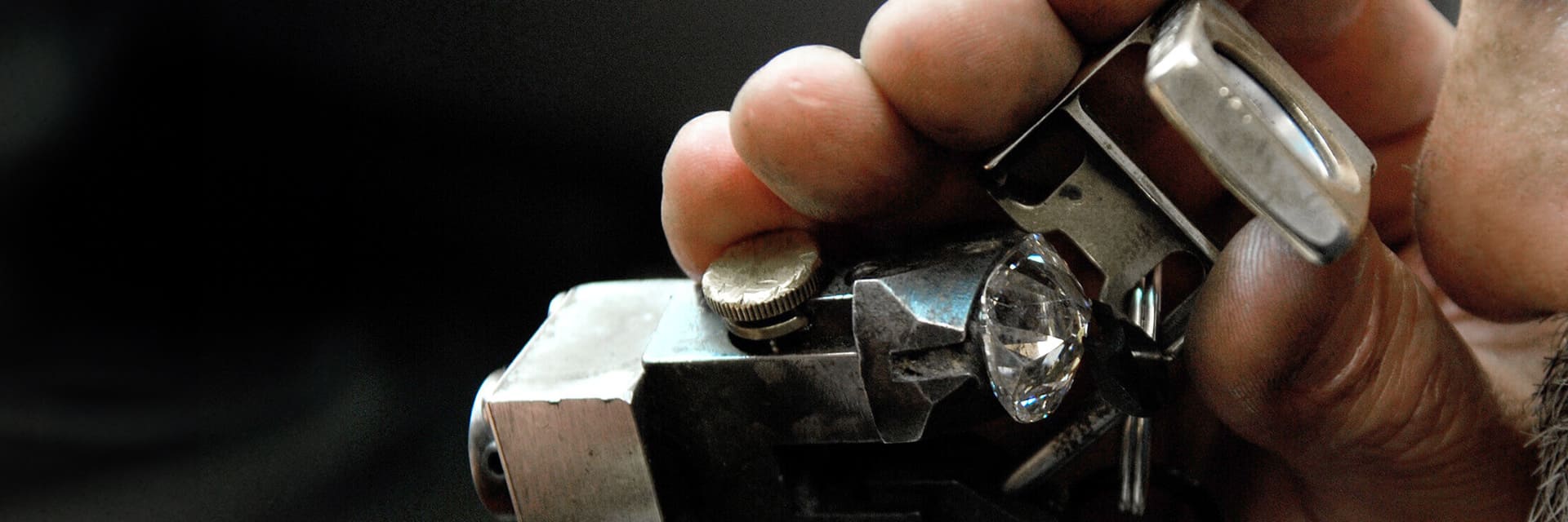 A man is looking through a diamond lens to inspect a diamond