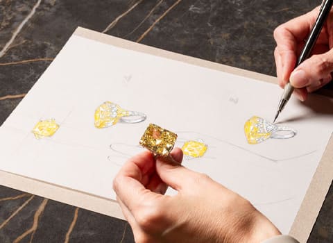 A woman is holding an amber colored diamond