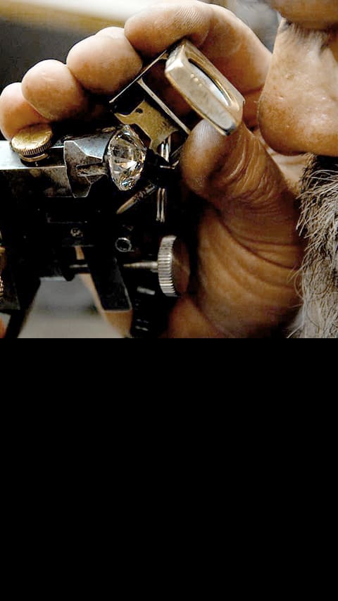 A man is looking through a diamond lens to inspect a diamond