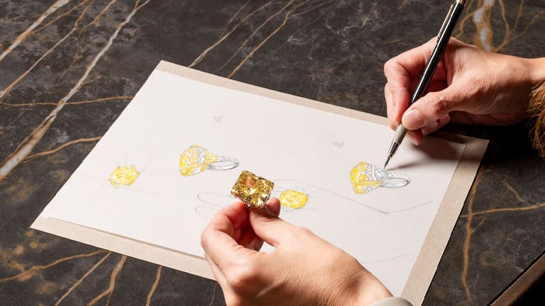 A woman is holding an amber colored diamond