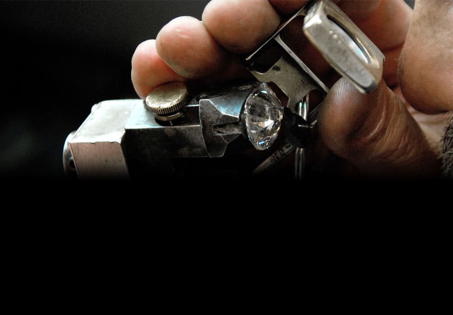 A man is looking through a diamond lens to inspect a diamond