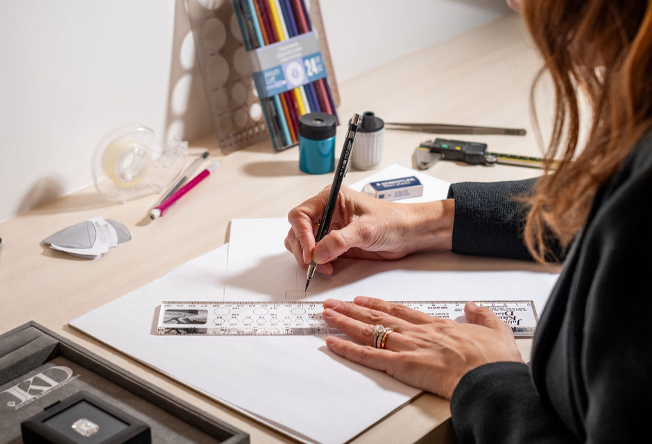 A woman is sketching designs for a diamond ring