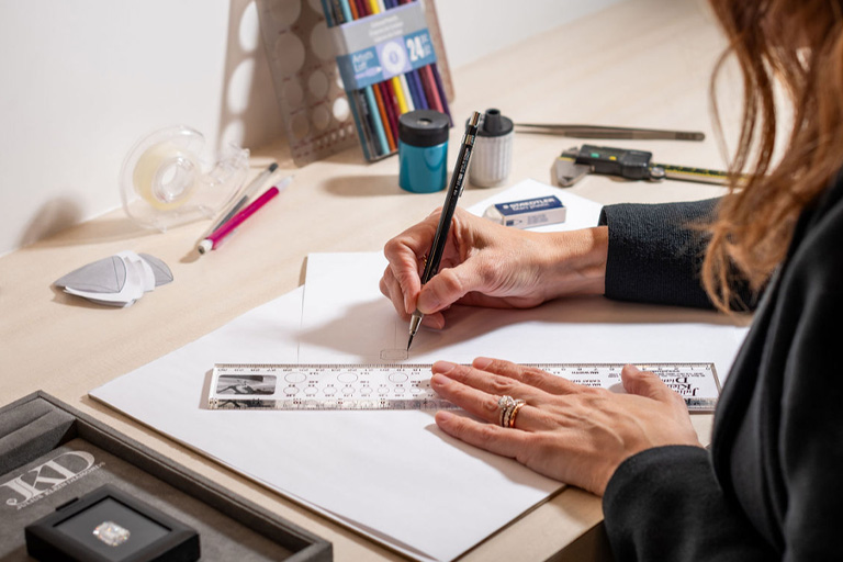 A woman is sketching designs for a diamond ring